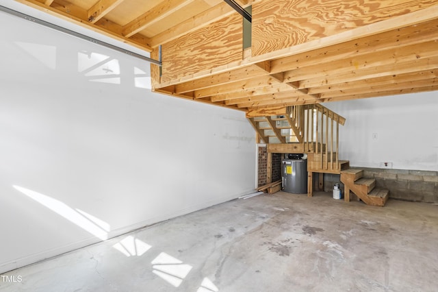 unfurnished living room with electric water heater, stairway, and unfinished concrete floors