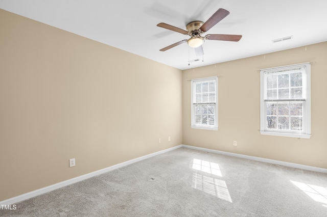 unfurnished room with carpet floors, baseboards, visible vents, and a ceiling fan