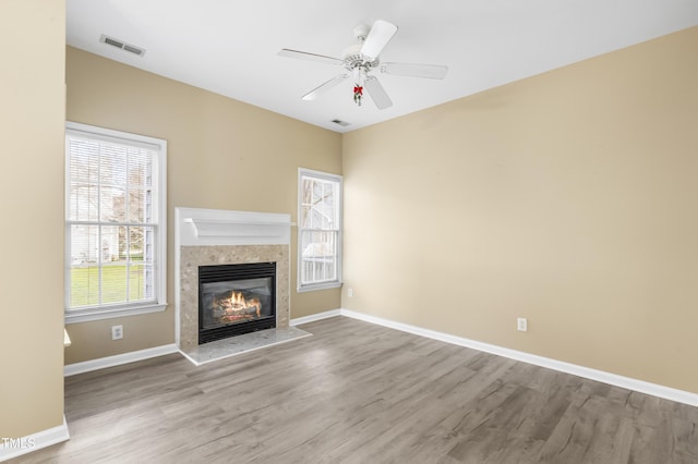 unfurnished living room featuring baseboards, visible vents, ceiling fan, wood finished floors, and a fireplace