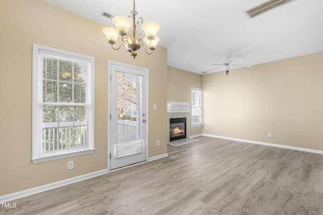 unfurnished living room with wood finished floors, a glass covered fireplace, visible vents, and baseboards