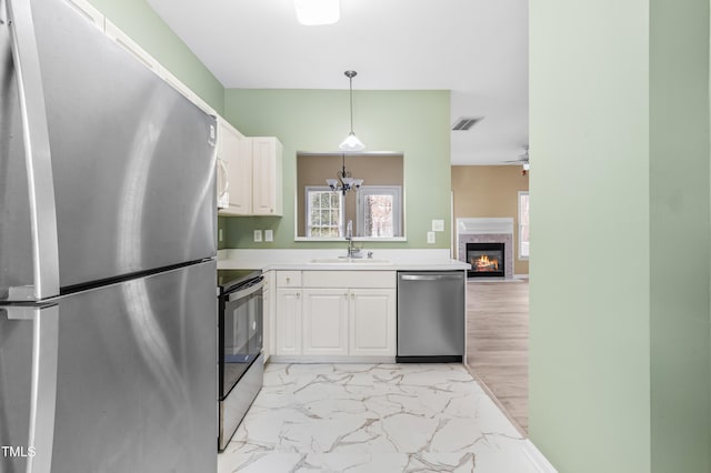 kitchen featuring appliances with stainless steel finishes, marble finish floor, white cabinets, and a sink