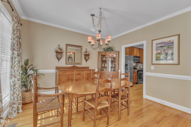 dining area with light wood-style floors, a wealth of natural light, ornamental molding, and an inviting chandelier