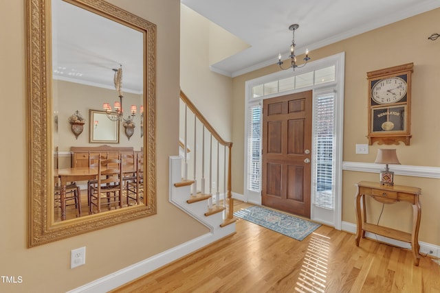 foyer entrance featuring an inviting chandelier, crown molding, and wood finished floors