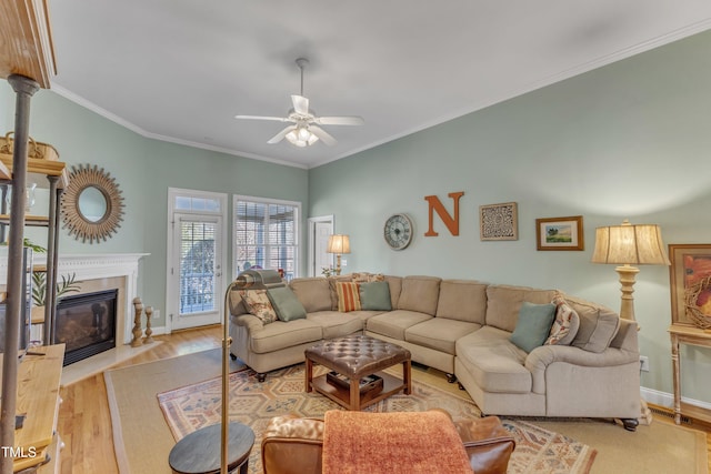 living room with ornamental molding, a fireplace, ceiling fan, and wood finished floors