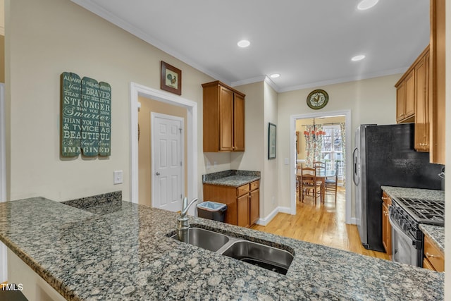 kitchen featuring range with gas cooktop, light wood-style flooring, ornamental molding, brown cabinets, and a sink