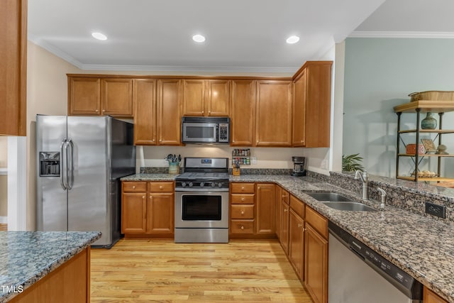 kitchen featuring brown cabinetry, dark stone counters, appliances with stainless steel finishes, crown molding, and a sink