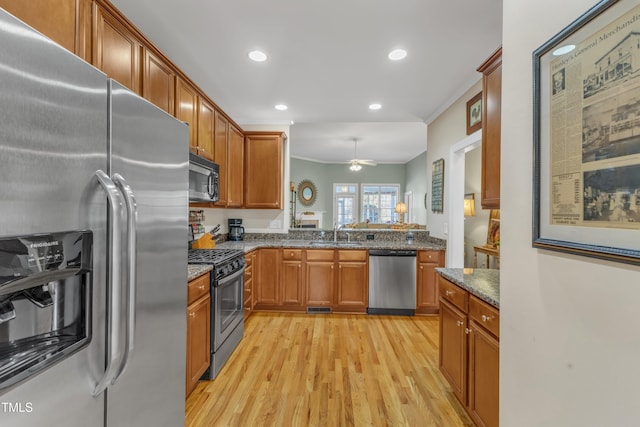 kitchen with appliances with stainless steel finishes, brown cabinetry, and dark stone countertops