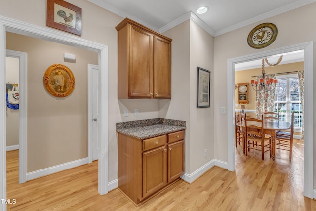 kitchen with light wood-style floors, baseboards, ornamental molding, and brown cabinetry