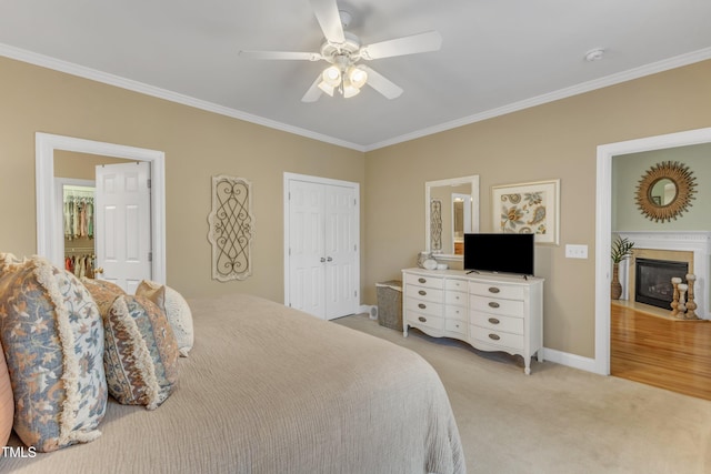 bedroom with crown molding, a closet, a fireplace with flush hearth, light carpet, and baseboards