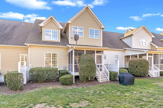 view of front facade with a sunroom, a shingled roof, and a front lawn