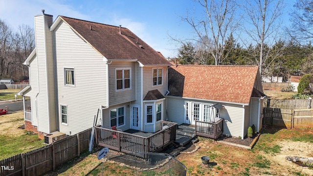 rear view of property featuring a deck, a fenced backyard, roof with shingles, and a chimney