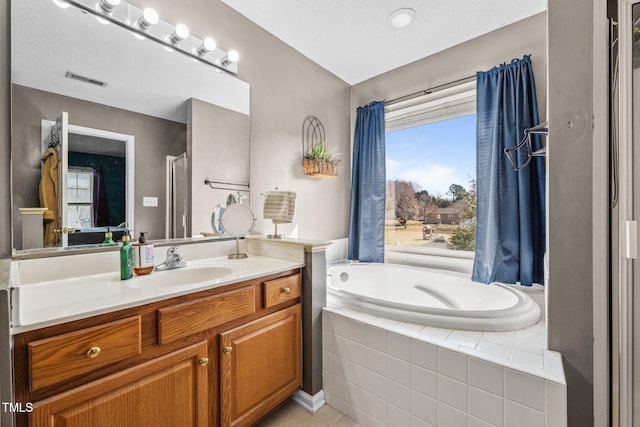 full bath with visible vents, vanity, and a garden tub