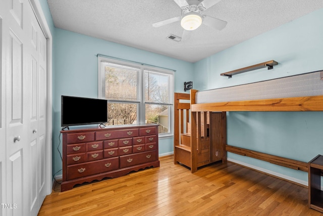 bedroom featuring a closet, visible vents, light wood-style flooring, and a textured ceiling