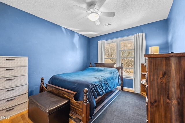 bedroom featuring carpet, a ceiling fan, visible vents, and a textured ceiling