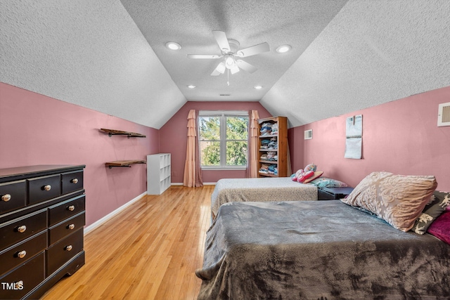 bedroom with ceiling fan, baseboards, lofted ceiling, light wood-style floors, and a textured ceiling