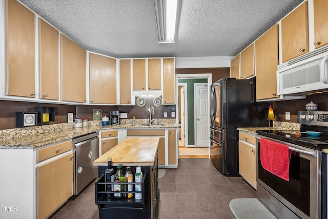 kitchen featuring dark tile patterned floors, butcher block counters, appliances with stainless steel finishes, a textured ceiling, and a sink