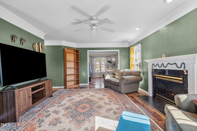 living room with baseboards, crown molding, ceiling fan, and wood finished floors