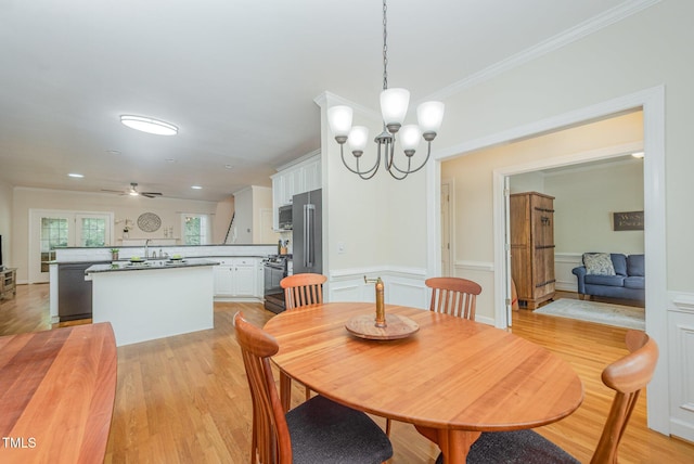 1208 Dunn Creek Xing, Wake Forest, NC 27587 - dining space with light wood-style floors, a chandelier, ceiling fan, crown molding, and wainscoting