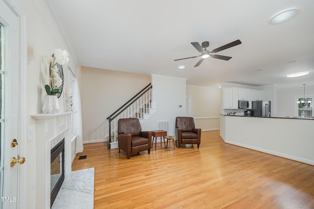 1208 Dunn Creek Xing, Wake Forest, NC 27587 - sitting room featuring light wood-type flooring, a ceiling fan, a premium fireplace, stairway, and baseboards