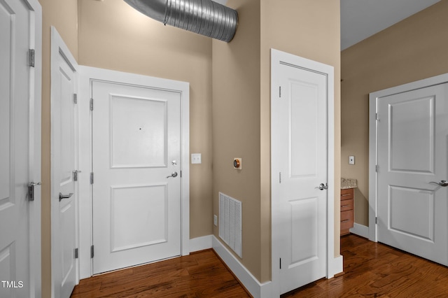 hallway featuring dark wood-style flooring, visible vents, and baseboards