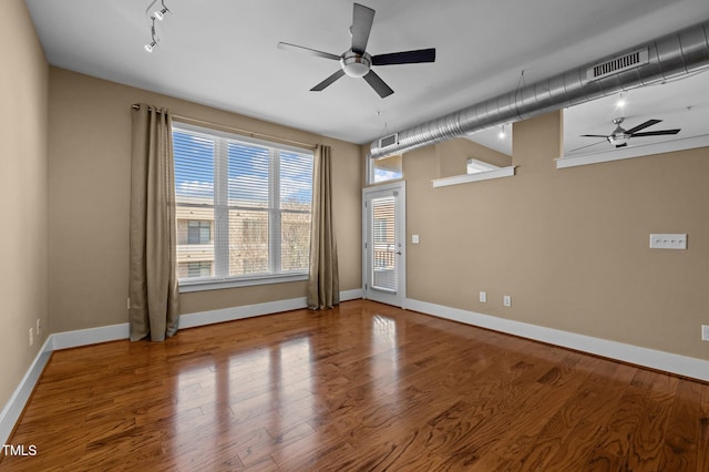 spare room with a ceiling fan, visible vents, and wood finished floors