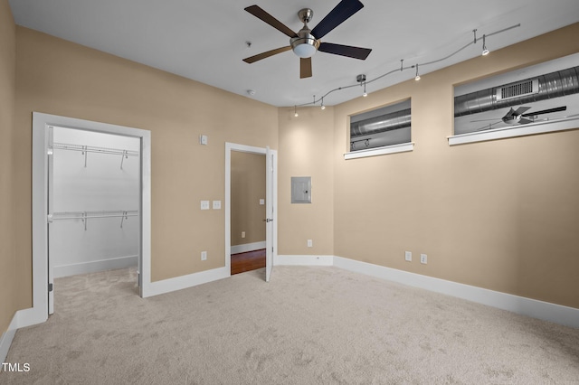 unfurnished bedroom with carpet floors, a spacious closet, electric panel, and track lighting