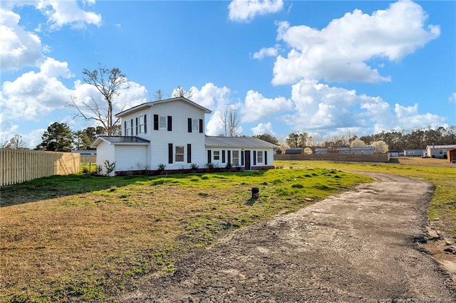 view of front of home with metal roof, a front lawn, and fence