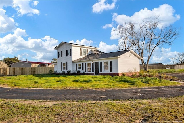 traditional-style house featuring metal roof, a front lawn, and fence