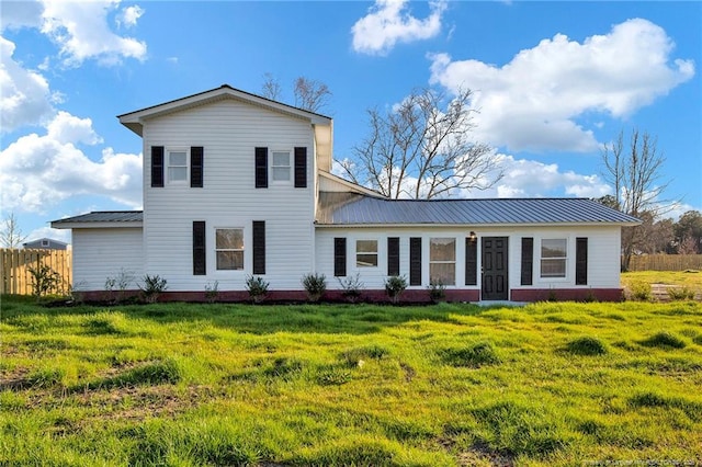 back of property with a yard, metal roof, and fence