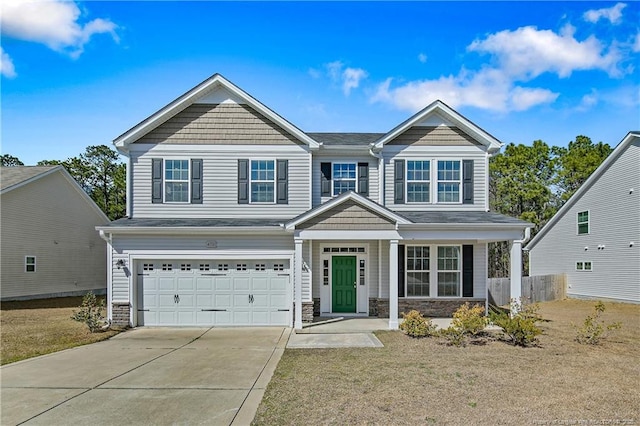 view of front of home featuring a garage, concrete driveway, fence, and stone siding