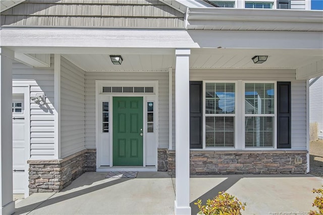 entrance to property with a porch and stone siding