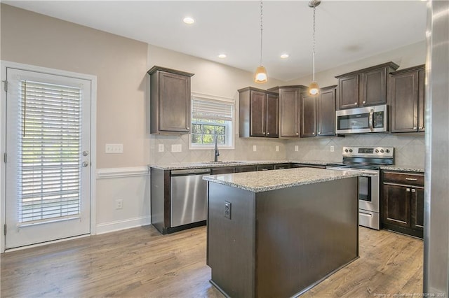 kitchen featuring light wood finished floors, stainless steel appliances, dark brown cabinets, and a sink