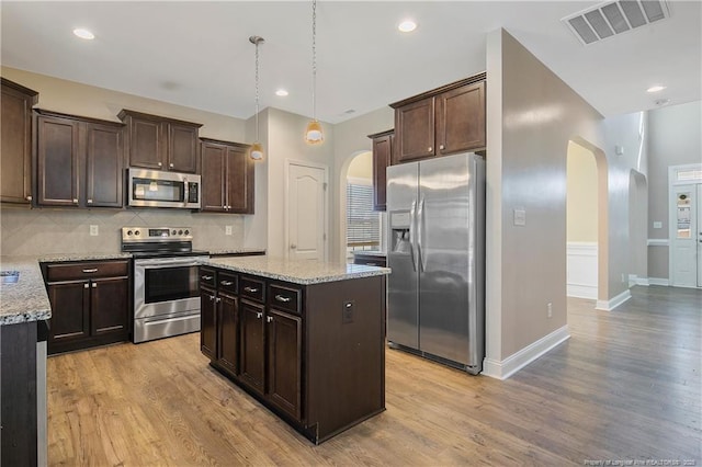 kitchen with dark brown cabinetry, visible vents, arched walkways, and stainless steel appliances