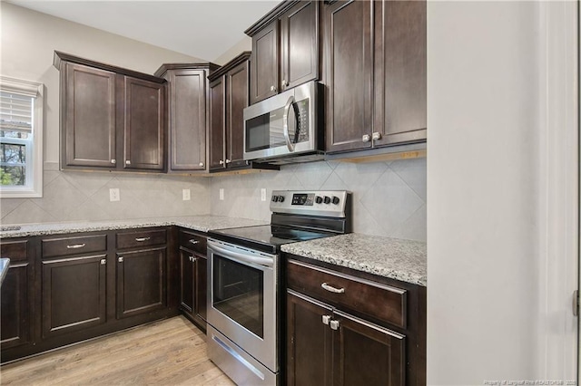 kitchen with appliances with stainless steel finishes, backsplash, light wood-style flooring, and dark brown cabinetry