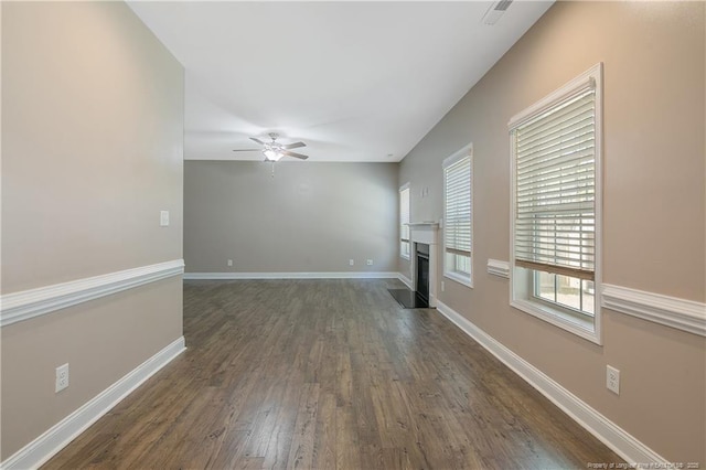 unfurnished living room with dark wood-style flooring, visible vents, a fireplace with flush hearth, ceiling fan, and baseboards