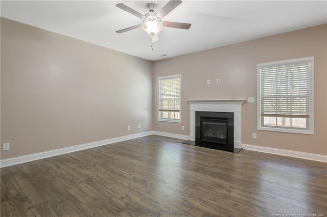 unfurnished living room with dark wood-style floors, a fireplace with flush hearth, baseboards, and a ceiling fan