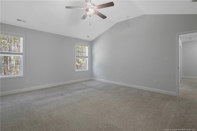 spare room with light colored carpet, a wealth of natural light, visible vents, and lofted ceiling