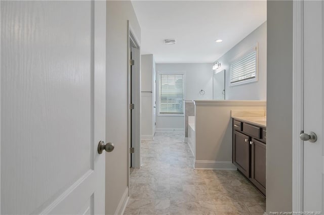 full bathroom featuring a garden tub, vanity, and baseboards