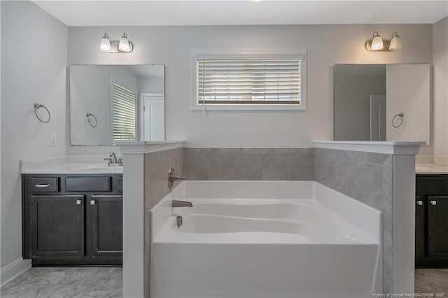 full bath with marble finish floor, a garden tub, and vanity