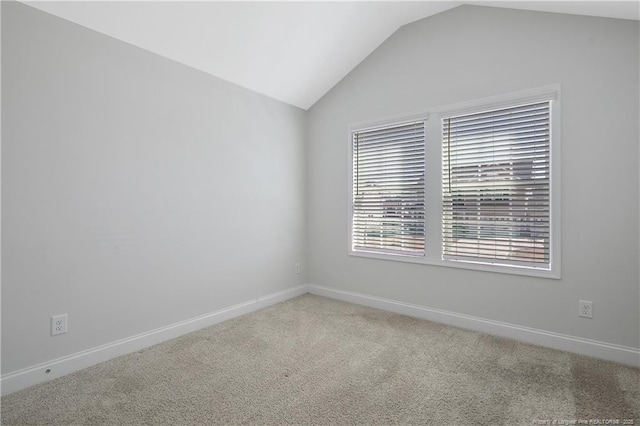 empty room with light carpet, baseboards, and vaulted ceiling