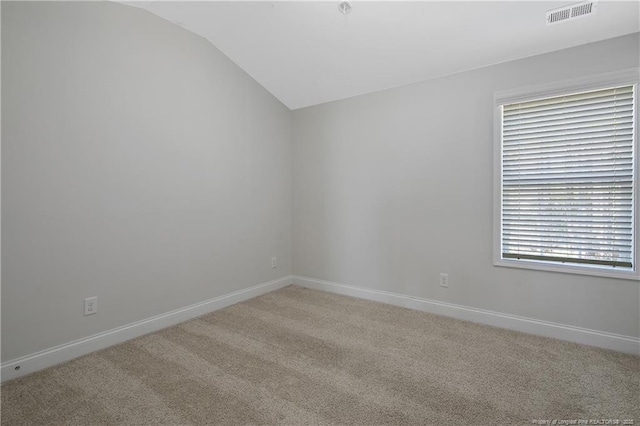 spare room with lofted ceiling, light carpet, visible vents, and baseboards