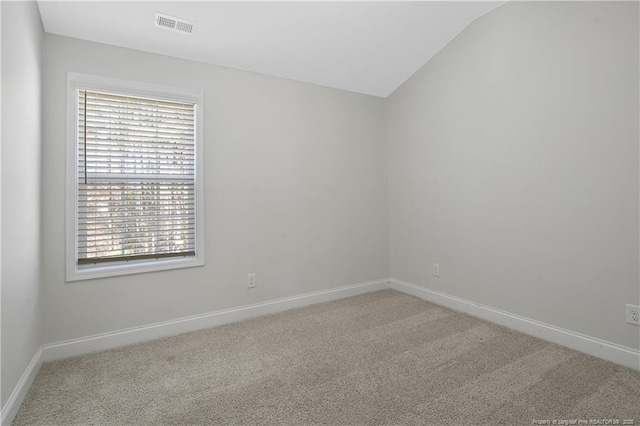 carpeted empty room with vaulted ceiling, visible vents, and baseboards