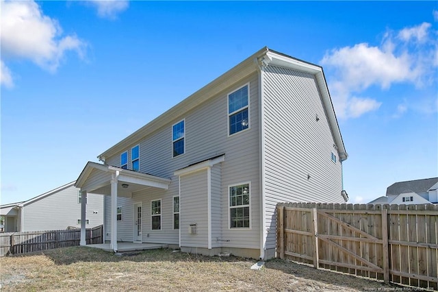 rear view of house featuring a patio area, fence, and a gate