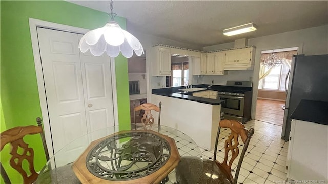 107 Oakmont Dr, Clinton, NC 28328 - kitchen with under cabinet range hood, a sink, dark countertops, a peninsula, and appliances with stainless steel finishes