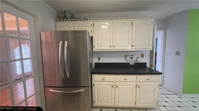 107 Oakmont Dr, Clinton, NC 28328 - kitchen with baseboards, dark countertops, light floors, white cabinetry, and freestanding refrigerator