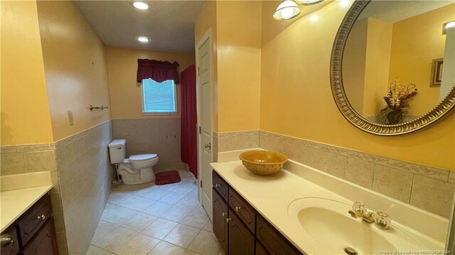 107 Oakmont Dr, Clinton, NC 28328 - bathroom featuring tile walls, a wainscoted wall, double vanity, toilet, and a sink