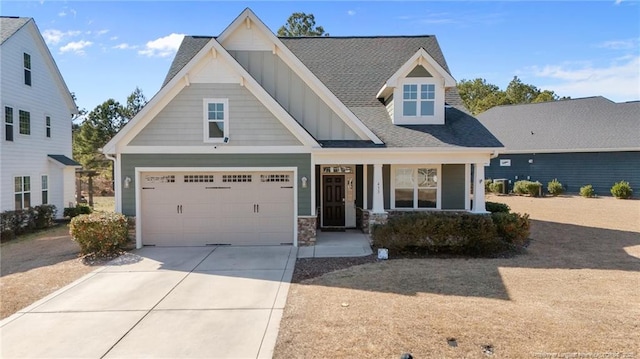 craftsman house featuring a shingled roof, covered porch, board and batten siding, a garage, and driveway