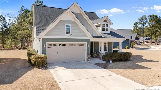 craftsman-style home with a garage, concrete driveway, a shingled roof, and board and batten siding