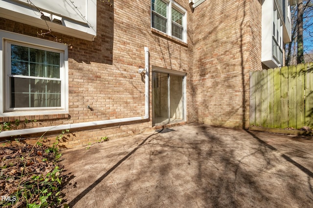 exterior space featuring a patio area, brick siding, and fence