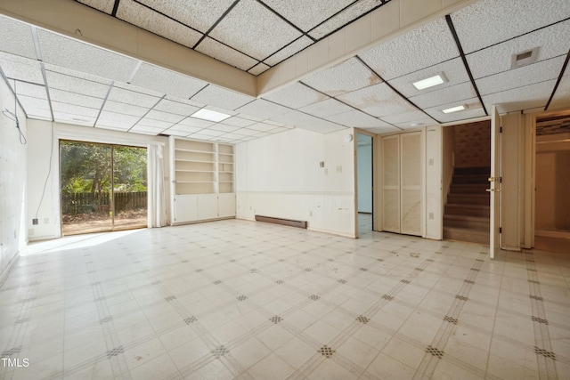 spare room with stairs, baseboard heating, a drop ceiling, and tile patterned floors